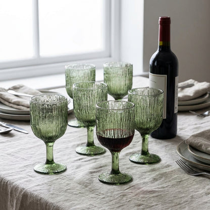 Seis tacas de vinho Moss Ripple em vidro reciclado verde-musgo, numa mesa posta com toalha de linho e garrafa de vinho