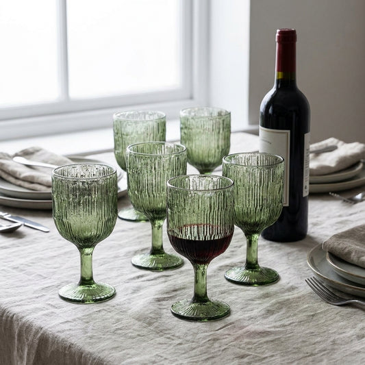 Seis tacas de vinho Moss Ripple em vidro reciclado verde-musgo, numa mesa posta com toalha de linho e garrafa de vinho