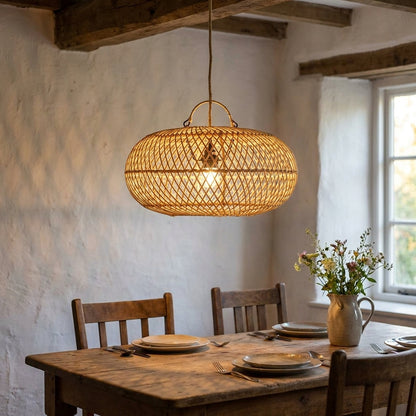 Candeeiro pendente Wholly em rattan natural aceso sobre uma mesa rustica, com sombras rendilhadas na parede