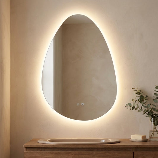 Espelho Kiama de forma organica com retroiluminacao LED acesa e botoes tacteis, sobre movel de lavatorio em madeira