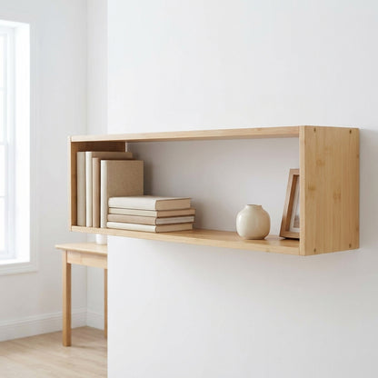 Prateleira-caixa Ember em bambu natural montada numa parede branca, com livros deitados, um vaso de cerâmica e uma moldura pequena