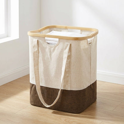 Saco de roupa Noto com armação de bambu e alças compridas, corpo cru e castanho, no chão de um quarto claro