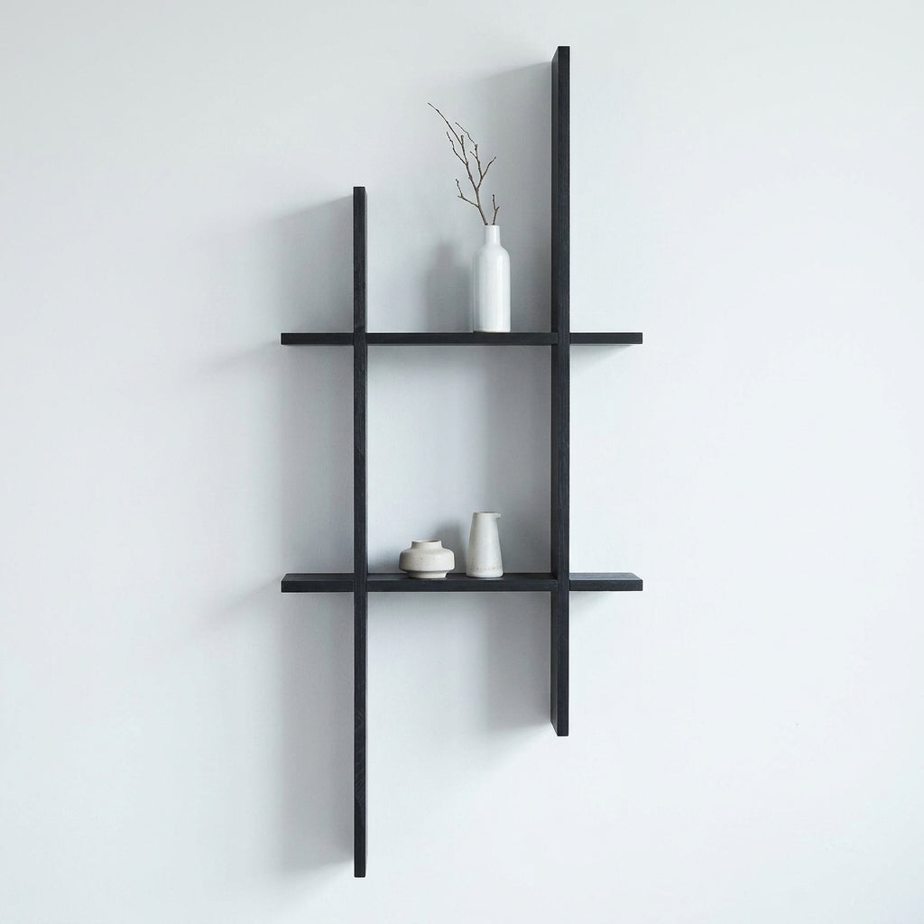 Prateleira de parede Mostar em pinho preto montada numa parede clara, com objectos decorativos
