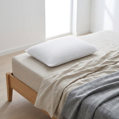 Almofada de dormir baixa com malha arejada, branca, 50 × 70 cm, numa cama de madeira clara