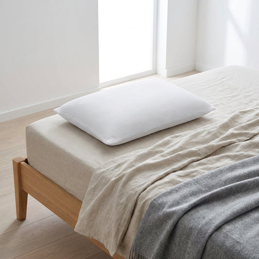 Almofada de dormir baixa com malha arejada, branca, 50 × 70 cm, numa cama de madeira clara