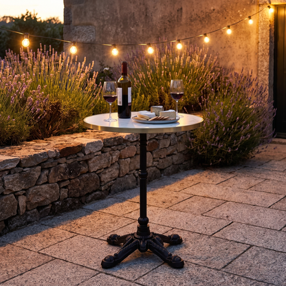 Mesa bistrô com tampo em mármore branco e pés em ferro fundido num jardim