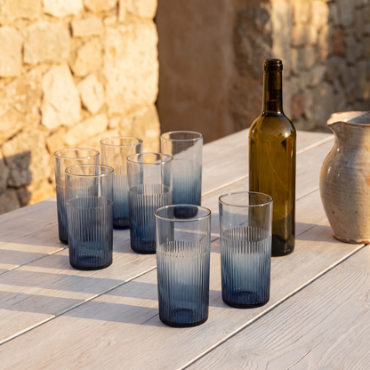 Seis copos altos ondulados Azure em vidro reciclado azul num terraco mediterranico