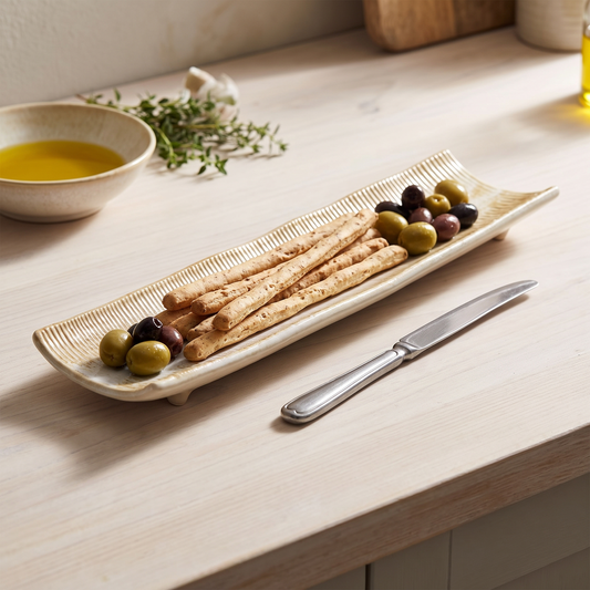 Travessa longa Da Rocha em ceramica branco-mel com palitos de pao e azeitonas