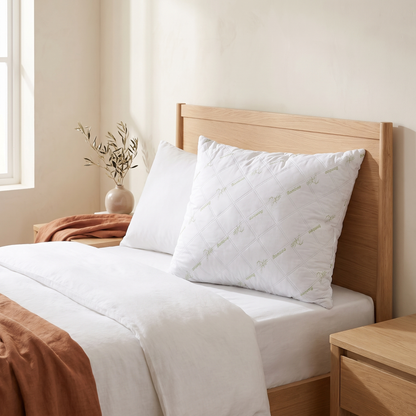 Almofada de dormir toque de bambu branca numa cama, quarto quente em tons creme e terracota